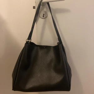 Väska - Jag säljer en väska från Vero Moda som nästan är som ny och bara har använts i en månad.  Höjd: 27 cm  Längd: 31 cm  Vidd: 17.5 cm  Handtag: 27 cm  