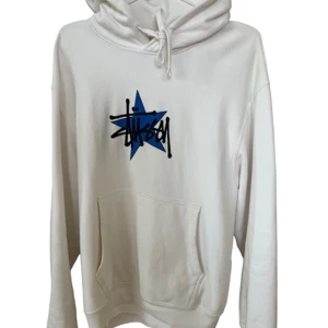 Vit hoodie från Stussy - Star Hoodie Pigment Dyed från Stussy i storlek small. Den har en cool blå stjärna med Stussy-loggan på framsidan. Perfekt för en avslappnad stil och passar till alla årstider. Den är i bra skick och superbekväm att ha på sig. Perfekt för både vardag