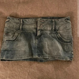 Lågmidjad minikjol -denim  - Lågmidjad mini-jeanskjol. Köpt på marknad i Spanien, så står inte storlek. Passar mig bra (se bild), vid behov kan jag mäta den! 
