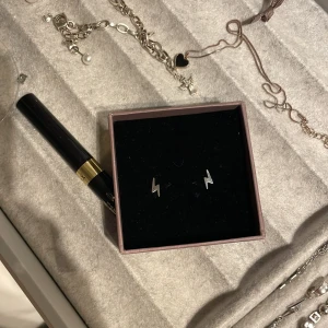 Blixtformade örhängen från Edblad - Säljer ett par coola blixtformade örhängen från Edblad. De är i silverfärg och kommer i en snygg rosa ask. Perfekta för att ge din outfit en edgy touch! 💥