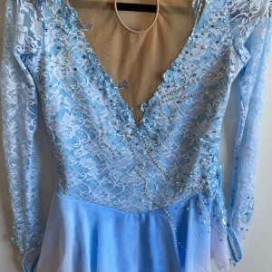 Konståkningsklänning - En jättefin blå glittrig Konståkningsklänning,använd 1-2 gånger, nypris ca 1700 säljer för 600 pris kan diskuteras💕storlek 14-16 år ,(S)