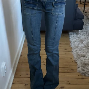 Lågmidjade Bootcut Jeans - I modellen ”low waist bootcut pocket jeans” från nelly, i nyskick endast använda 2 ggr!  Nypris 700kr