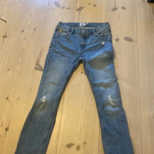 Jeans med slitningar  - Jag säljer nu dessa snygga jeans med slitningar (väldigt trendigt). Säljer dessa pga  att de är för små helt enkelt de är inte alls särkilt använda och är därför i topp skick. Byxorna är från lager 157 kommer därför sälja dessa rätt billigt.