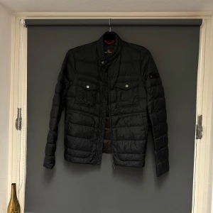 Snygg dunjacka från Peuterey - Säljer en snygg svart märkesjacka från Peuterey i storlek S. Jackan har en stilren design med dragkedja och knappar framtill. Perfekt för höst och vår, med långärmade ärmar och en quiltad look. Den är sparsamt använd och i bra skick 😊