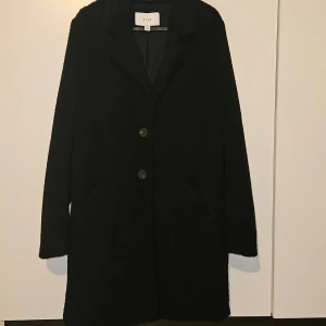 Teddy kappa - En svart mjuk och gosig kappa från Vila som är använd fåtal gånger. Den är som ny i skicket, har djupa fickor och 2 knappar. Pris går att diskutera vid smidigt affär!