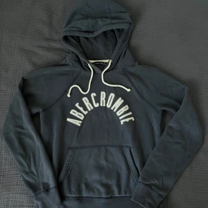 Hoodie från Abercrombie & Fitch - Mörkblå hoodie/huvtröja från Abercrombie & Fitch i mycket fint skick. Storlek small.  Kommer från ett djur- och rökfritt hem.