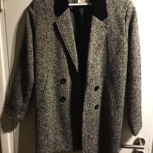 Kavaj Pins and needles XS - En gråmelerad dubbelknäppt kavaj i ullblandning från Pins and needles. Storlek XS. Krage i sammet, fickor i sidan, fodrad. Längd:  80 cm, axlar: 42 cm, bröst: 49 cm, midja: 47 cm, höft: 44 cm. Inga skavanker eller slitningar! 