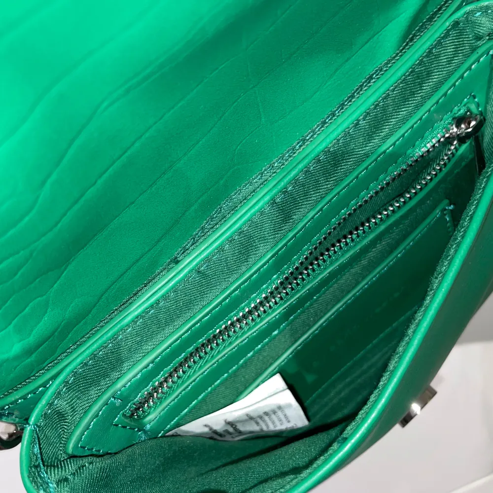 Snygg grön axelväska i syntetmaterial med justerbar rem. Perfekt för att ge en färgklick till din outfit! Väskan har en praktisk dragkedja inuti för säker förvaring av dina saker. Passar både till vardags och festliga tillfällen.. Laukut & Käsilaukut.