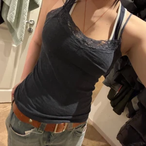 Mörkblått linne med spetsdetaljer - Säljer en mörkblå linne med justerbara axelband och fina spetsdetaljer vid halsringningen. Perfekt för lager-på-lager! skön o stretchig, passar xs-m!