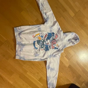 Cool hoodie med tryck!🫶 - Säljer en cool vit och blå hoodie med ett färgglatt grafiskt tryck på framsidan och baksidan ❤️Hoodien har en stor ficka framtill och en bekväm huva.100% bomull!💗storlek S herr, men passar mig bra som har M! Köp via köp nu eller swish!🫶