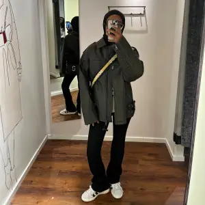 Snygg grön skinnjacka med dragkedja och krage. Jackan har en oversized passform och långa ärmar. Perfekt för en cool och avslappnad stil. Bilderna är tagna i provrummet innan jag köpte den. Inte använd!! Köpt för 1000kr.