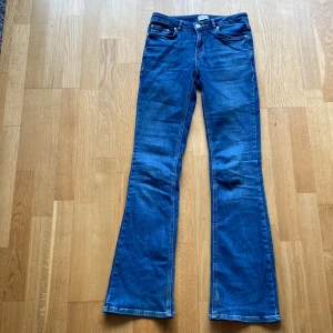 Blå bootcut jeans från Grunt - Strlk: 28. Snygga blå bootcut jeans från Grunt, femficksdesign och knappgylf. Material: 98% bomull, 2% elastan. Style: Texas Low Flare.