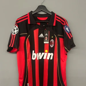 AC Milan fotbollströja med Kaka 22 - Snygg AC Milan fotbollströja från Adidas med Kaka's namn och nummer 22 i guld på ryggen. Tröjan är svart och röd med Champions League-märken på ärmarna. Perfekt för fans av Kaka och AC Milan! Storlek M och helt ny med tagg det är en replika. Kom gärna med prisförslag!