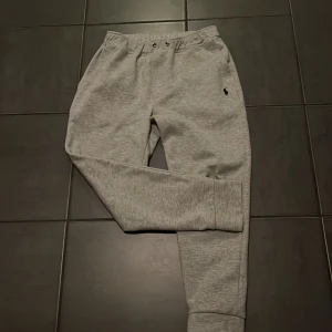 Grå mjukisbyxor från Polo Ralph Lauren - Snygga grå mjukisbyxor från Polo Ralph Lauren med elastisk midja och dragsko. Byxorna har en liten broderad logga på framsidan och en bakficka ibak. Priset går att diskutera🍾😁