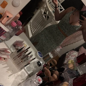 Grön blommig klänning - Snygg grön blommig klänning med en slits och smala axelband. Perfekt för sommarens varma dagar. Klänningen har en dragkedja i ryggen för enkel påklädning.