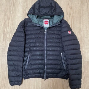 Svart pufferjacka från Colmar - Säljer en svart pufferjacka från Colmar med huva och dragkedja! 🙌Jackan är i bra skick med några enstaka småhål hit och dit, ingenting som syns när den bärs! 🙌Storlek 46 (S), Skriv vid minsta fråga eller fundering! 🤩