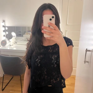 Marinblå spetsblus - Säljer en elegant marinblå spetsblus med korta ärmar. Blusen har ett vackert spetsmönster och är perfekt för en stilren look. Den är både chic och bekväm.