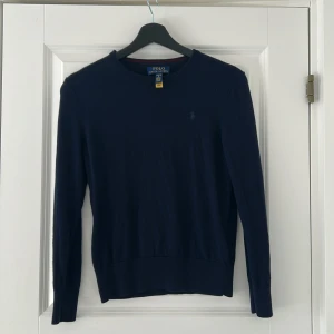 Mörkblå tröja från Ralph Lauren - Säljer en stilren mörkblå tröja från Ralph Lauren. Tröjan har långa ärmar och en klassisk rund halsringning. Perfekt för en avslappnad men ändå elegant look. 🧥