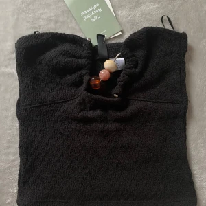 Svart tubtopp med pärldetaljer  - Snygg svart tubtopp från H&M med dekorativa pärlor framtill. Helt ny topp som kommer med prislappen. 