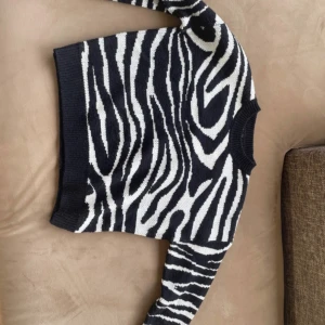 Zebramönstrad stickad tröja - Säljer en cool zebramönstrad stickad tröja i svart och vit. Tröjan har en normal passform med långa ärmar och ribbade kanter vid hals, ärmslut och nederkant. Perfekt för att ge din outfit en trendig touch 🖤