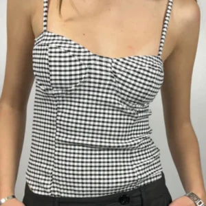 Svartvit rutig body - Snygg svartvit rutig korsett med smala axelband. Perfekt för en stilren look. Passar bra till både jeans och kjol. 