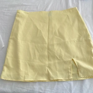 Gul kortkjol med slits - Snygg gul kortkjol i ett mjukt material med en liten slits framtill. Perfekt för soliga dagar och ger en fräsch look. Enkel design som är lätt att matcha med olika toppar.