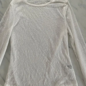 Vit ribbad genomskinlig topp - Säljer en stilren vit ribbad topp med långa ärmar. Perfekt för lager-på-lager eller som den är. Enkel och mångsidig design som passar till det mesta. Hör av dig vid intresse! 🤍