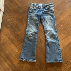 Blå bootcut jeans från Gina Tricot - Snygga blå bootcut jeans från Gina Tricot med klassisk femficksdesign och dubbla knappar i midjan. 