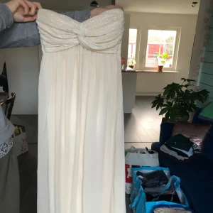 Champagnefärgad axelbandslös balklänning från Nelly Trend - Otroligt vacker balklänning från Nelly med glittrig överdel✨✨aldrig använd och i storlek S. Köparen står för frakt ✨💋