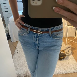Brunt skärp med gulddetalj - Snyggt brunt skärp i skinn med en stilren guldfärgad spänne. Perfekt för att ge en klassisk touch till din outfit. Passar bra till jeans och andra byxor.