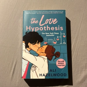 The Love Hypothesis - Säljer boken 'The Love Hypothesis' av Ali Hazelwood. En New York Times bestseller med en bonuskapitel. Perfekt för dig som gillar romantiska berättelser med en vetenskaplig twist. Boken har en blå omslag med illustration av ett par som kysser varandra.