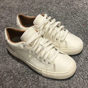 Vita sneakers med snörning - Snygga vita sneakers i skinn med klassisk design och snörning. Perfekta för en stilren look. De har en bekväm sula och en neutral färg som passar till det mesta.