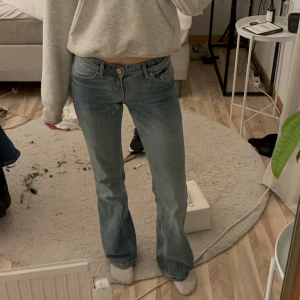 Blå bootcut/straght jeans - Snygga blå bootcut jeans med klassisk femficksdesign och knappgylf. Perfekta för en avslappnad stil. De har en bekväm passform och är tillverkade i ett slitstarkt denimtyg. Dem är små i storleken och ganska tajta men passar bra på mig. 