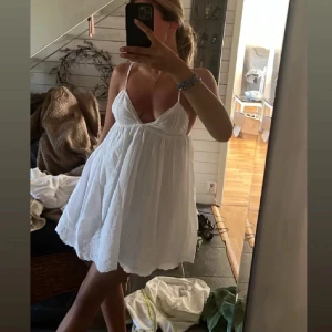 Vit sommarklänning med smala axelband från Zara - Charmig vit klänning med smala axelband och v-ringad design. Perfekt för varma sommardagar. Klänningen har en luftig passform och är tillverkad i ett lätt material. Storlek XS. Första två bilderna är lånade🔥💕 Super fin klänning verkligen