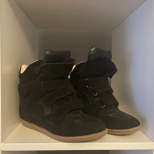 Svarta sneakers Isabel Marant Liknande AA  - Snygga svarta sneakers ”liknande” av isabel marant med hög design och kardborreband. Skorna har en stilren look med en beige sular.  Riktigt Mocka läder på skorna. Hör av dig om du har frågor.