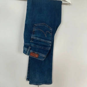 Blå jeans från LTB - W27 L34Snygga blå jeans från LTB med en klassisk femficksdesign och knappgylf. Jeansen har en tight passform och är perfekta för en avslappnad stil. De har en lätt slitning på framsidan för en trendig look. 