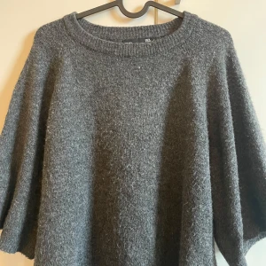 Grå stickad tröja - Mysig grå stickad tröja med trekvartsärm. Perfekt för kyliga dagar och ger en avslappnad look. Tröjan har en rund halsringning och är gjord i ett mjukt material som håller dig varm.