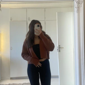 Brun stickad kofta från Zara - Säljer en snygg brun stickad kofta från Zara. Den är croppad med långa ärmar och har en öppen design framtill. Perfekt för lager-på-lager-stil under kyligare dagar.