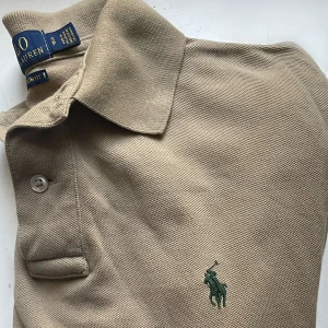 Ralph Lauren | Piké (sällsynt) - Ralph Lauren Piké | Beige, med skogsgrön logga. Stört snygg! | En ovanlig färgkombination, lycka till med att hitta en likadan | Nypris 1299:- 🚨 Säljer lite dyrare pga av dess sällsynthet 🚨