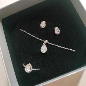 Smyckeset i silver med droppformade stenar - Elegant smyckeset i silver med ett halsband, örhängen och en ring i storlek 17 med matchande droppformade stenar. De är i äkta silver och är märkta. Helt oanvända då jag inte använder silver. Nypris var runt 500, pris kan diskuteras.