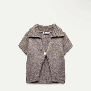 Beige stickad kofta från Zara - Säljer en snygg beige stickad kofta från Zara. Den har korta ärmar och en stor knapp framtill. Perfekt för lager-på-lager och ger en avslappnad look. Passar bra till jeans eller kjol.