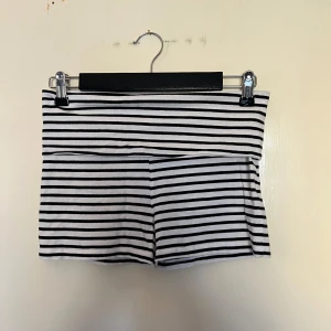 Randiga shorts från Gina Tricot - Snygga svartvita randiga shorts från Gina Tricot. Perfekta för en avslappnad stil med en elastisk midja för extra komfort. Passar bra till sommarens varma dagar. Gina Young storlek 158/164 men passar som Xs/s.