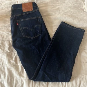 Levis 501 jeans i mörkblå denim - Klassiska Levis 501 jeans i mörkblå denim. Dessa jeans har en rak passform och är lätta att stylea. 