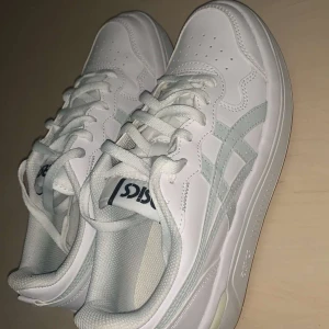 Vita sneakers från Asics - Snygga vita sneakers från Asics med klassisk design och snörning. Skorna har en stilren look med Asics-logga på plösen och sidorna. Perfekta för en casual stil.