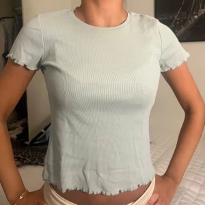 Ljusblå ribbad t-shirt - Fin ribbad t-shirt, små volanger i ärmar och nertill💙