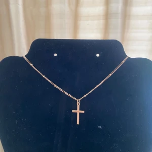 Guldfärgat halsband med kors -  ett  guldfärgat halsband med ett enkelt korshänge. Perfekt för både vardag och finare tillfällen  Kedjan är tunn, vilket gör det lätt att matcha med andra halsband💞