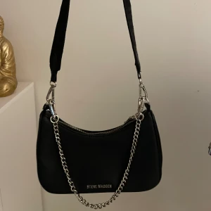 steve madden väska - svart steve madden väska köpt från zalando för 1000. Den är använd lite  men ser helt ny ut, inga skador eller så. Kedjan och lilla väskan är avtagbar
