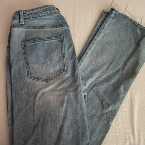 Blå jeans från Shein - Säljer ett par snygga blå jeans från Shein. De har en avslappnad passform med slitna detaljer och råa kanter vid bensluten. Perfekta för en casual look! 🕶️