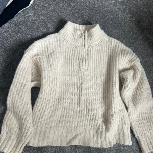 Beige stickad tröja med dragkedja - Säljer en supermysig beige stickad tröja med en halv dragkedja vid halsen. Perfekt för kyliga dagar och har en skön, avslappnad passform. Den är långärmad och passar perfekt till både jeans och kjol. Ett måste för höst- och vintergarderoben! 🍂❄️