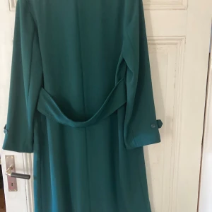 Lång kappa  - Blågrön kappa som faller fint. Mycket fint skick. Känns mer som strl 40 än 38.